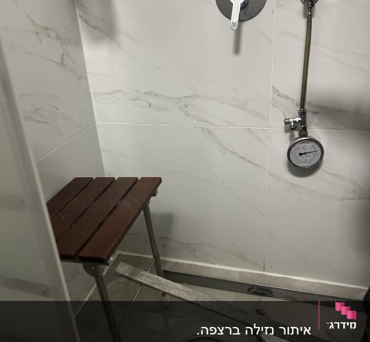 תמונה של מקלחת עם מד לחץ מים וסולם